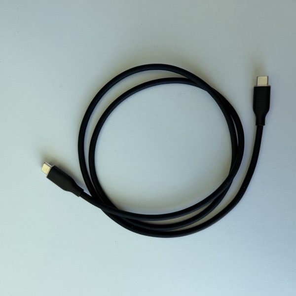 Anker 240W USB-C cable, black, coiled on a white desk with both USB-C connectors visible.