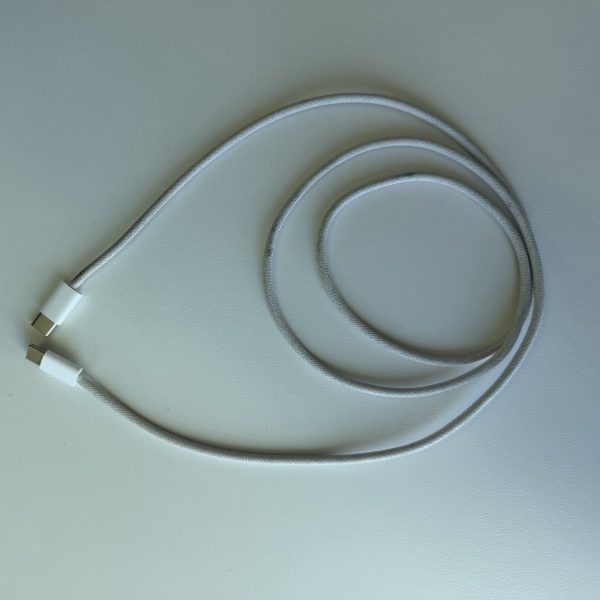 Apple 60W USB-C Woven Charge Cable, white, laid out on a desk, with grey marks worn into the woven sleeve.