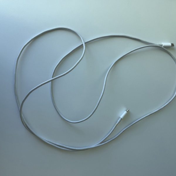 Apple 2 m USB-C Charge Cable, white rubber jacket, laid out in loops on a desk, discoloured with use.