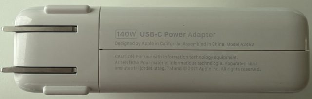 140W USB-C Power Adapter. Designed by Apple in California, Assembled in China. Model A2452. TM and copyright 2021 Apple Inc.